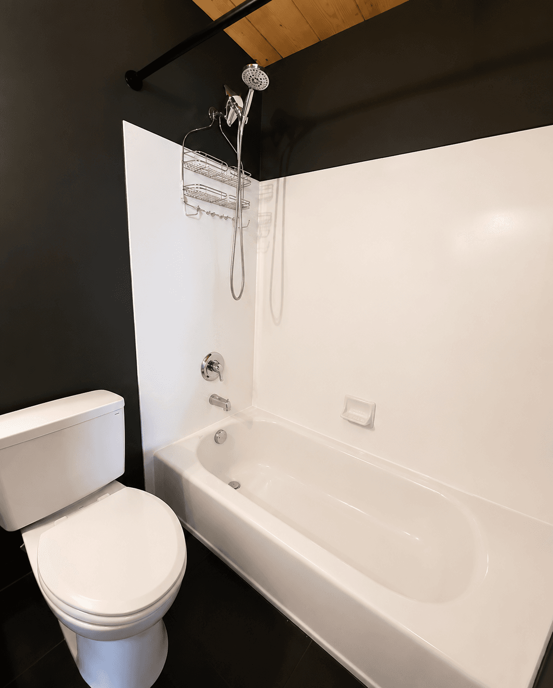 Clean white bathtub, shower, and toilet in a bathroom finished by ShinySpaces