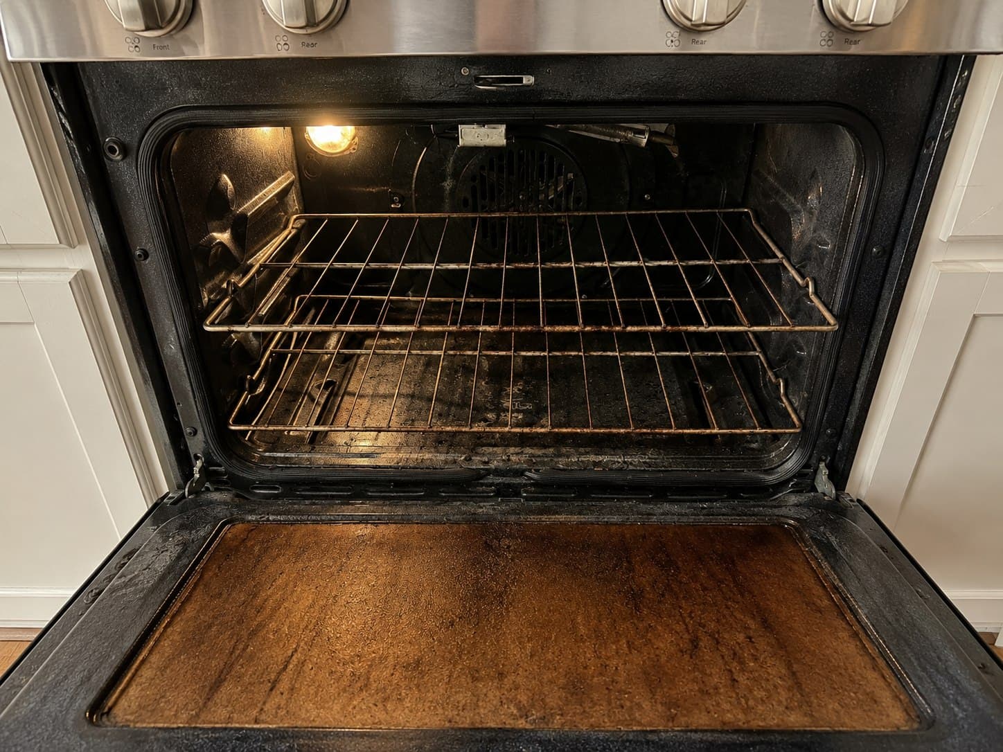 Oven interior before a ShinySpaces deep cleaning, with baked-on grease and residue on the racks and floor