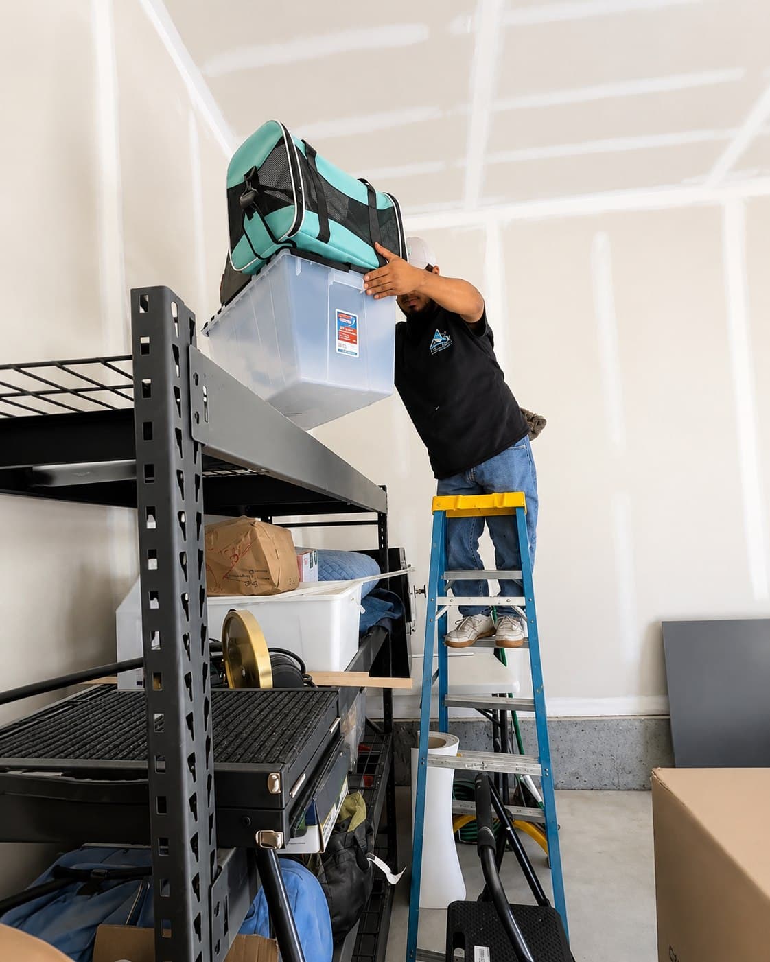 A ShinySpaces cleaner organizing high garage shelving during a move-in/move-out cleaning