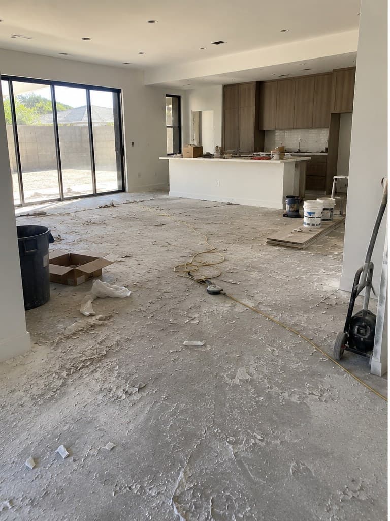 Open-concept room mid-renovation before a ShinySpaces post-construction cleaning, with dust and debris covering the concrete floor