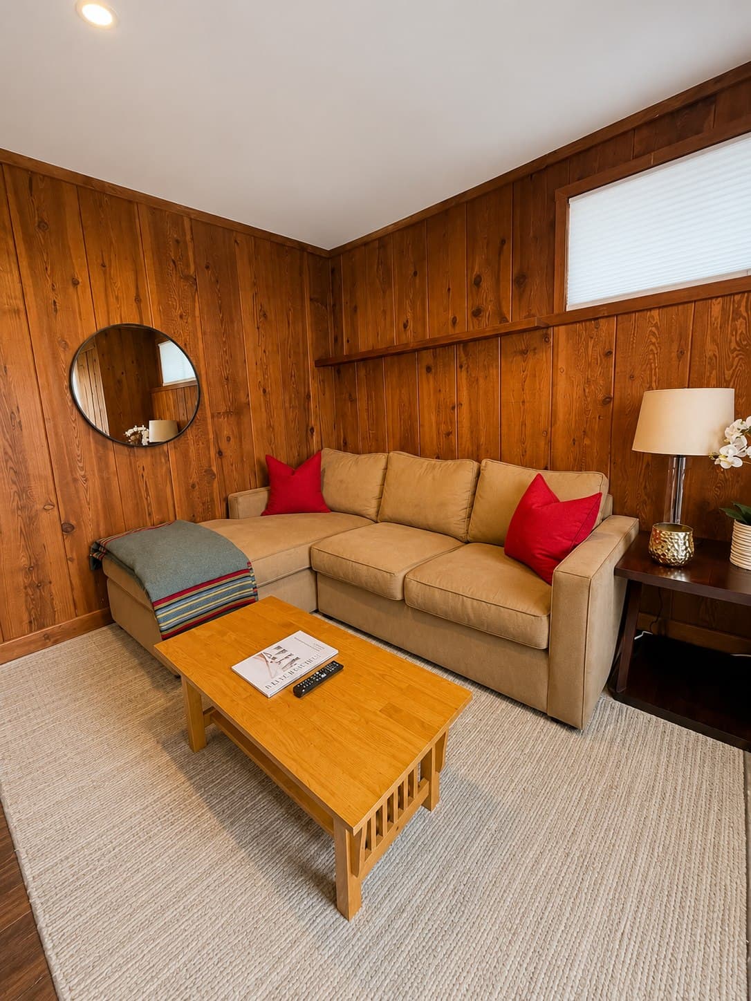 Cozy wood-paneled living room with a tidy sectional sofa and rug after a ShinySpaces residential cleaning